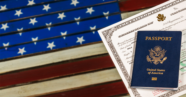 A U.S. passport and certificate of naturalization placed on a wooden surface painted with the American flag design.