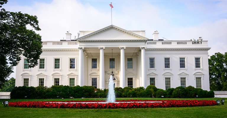 The White House with its iconic columns, fountain, and manicured lawn, symbolizing American democracy and leadership.